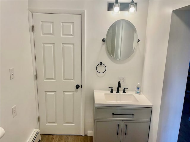 bathroom with hardwood / wood-style floors, a baseboard heating unit, and vanity