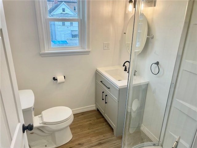 bathroom with toilet, a shower with shower door, wood-type flooring, and vanity