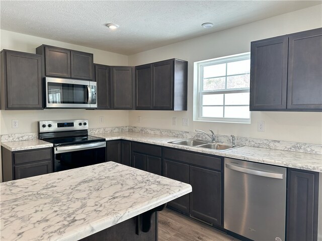 kitchen with a textured ceiling, stainless steel appliances, hardwood / wood-style floors, and sink