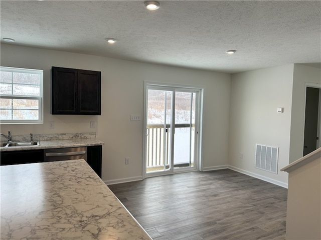 kitchen featuring light stone countertops, a textured ceiling, dishwasher, dark hardwood / wood-style flooring, and sink