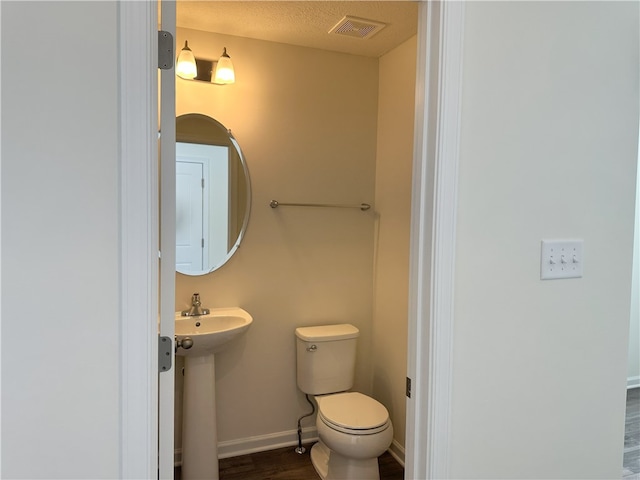 bathroom featuring toilet, a textured ceiling, wood-type flooring, and sink