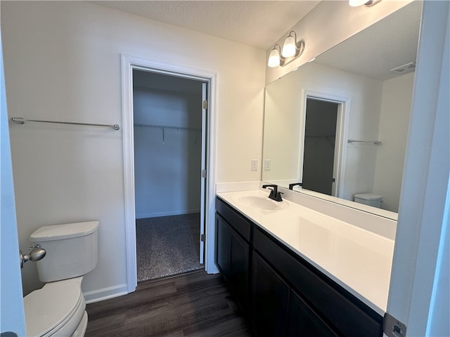 bathroom featuring wood-type flooring, toilet, vanity, and a textured ceiling