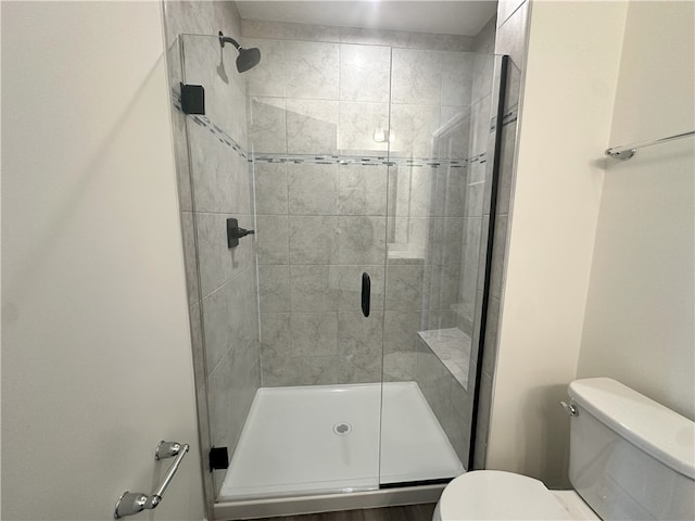 bathroom with a shower with shower door and toilet