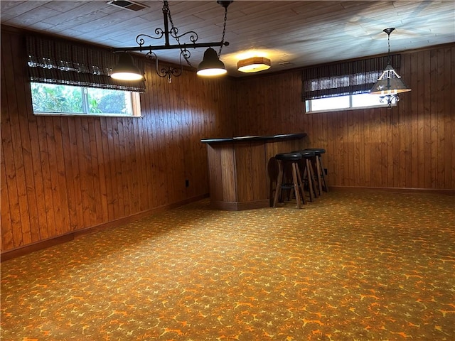 bar with wood walls, plenty of natural light, and hanging light fixtures