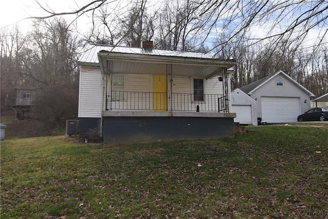 view of front of home with a front yard, a garage, a porch, and an outbuilding