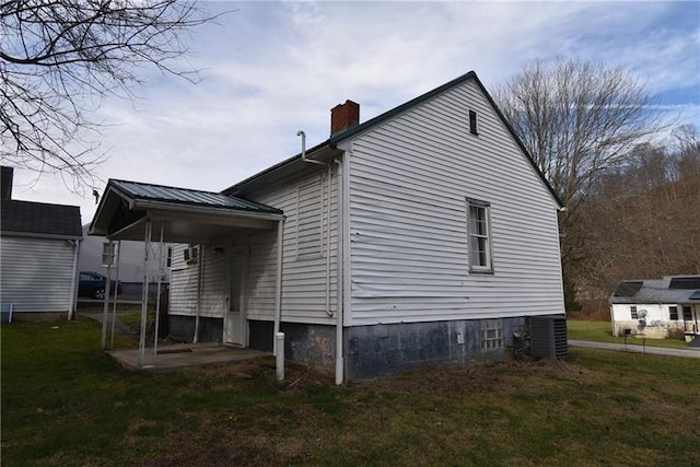 view of side of home featuring a lawn and central AC