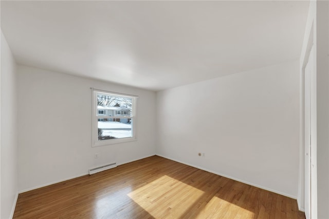 unfurnished room with a baseboard heating unit and hardwood / wood-style flooring