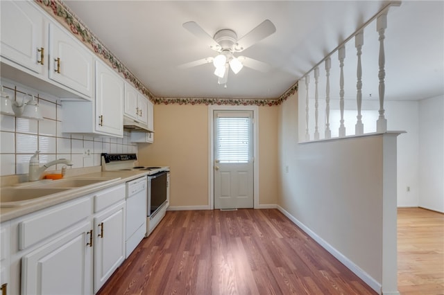 kitchen with decorative backsplash, sink, white cabinetry, and electric range oven