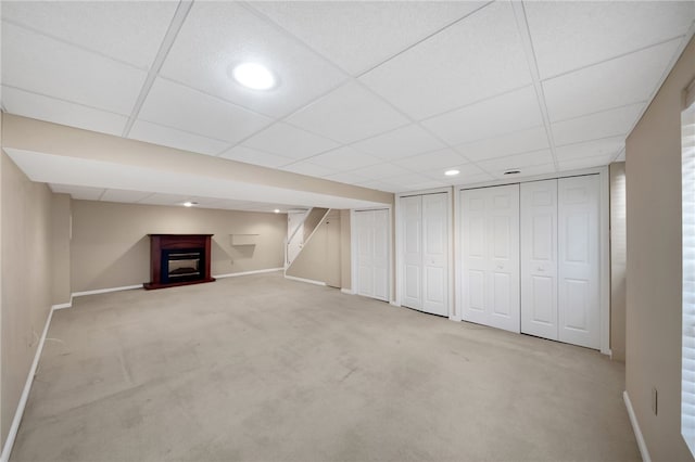 basement featuring light carpet and a paneled ceiling