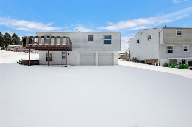 snow covered house with a garage and a deck