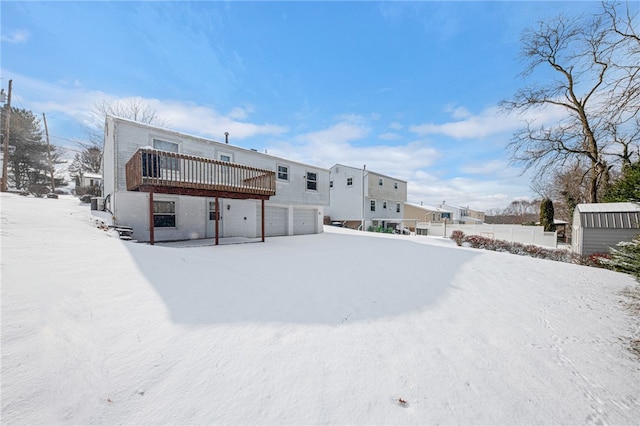 snow covered property with a wooden deck and a garage