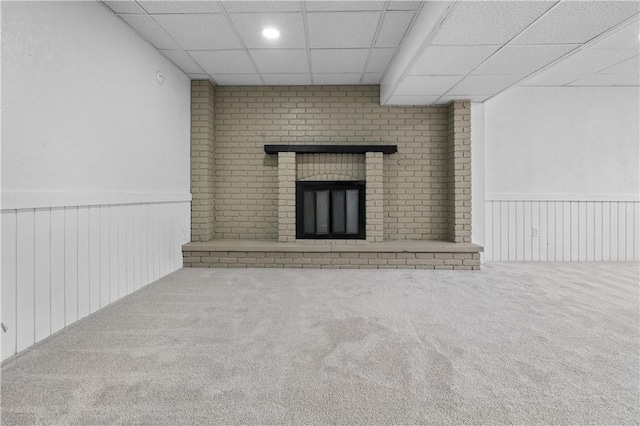 unfurnished living room with carpet, a paneled ceiling, and a fireplace