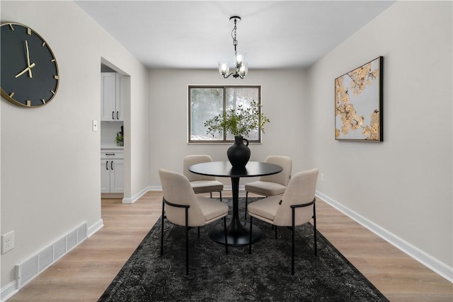 dining room featuring light wood-type flooring and a notable chandelier