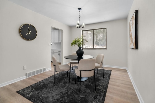 dining room featuring light wood-type flooring and a chandelier