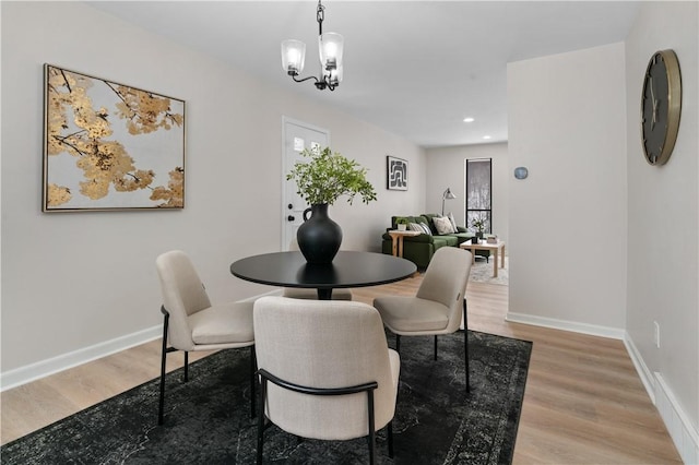 dining space with light hardwood / wood-style floors and a chandelier