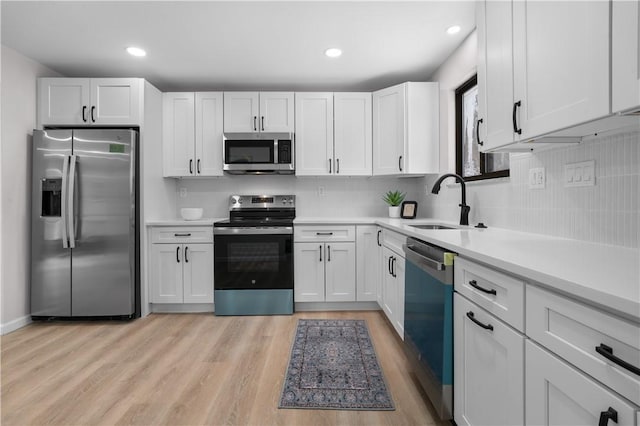 kitchen featuring stainless steel appliances, light hardwood / wood-style flooring, white cabinets, and sink