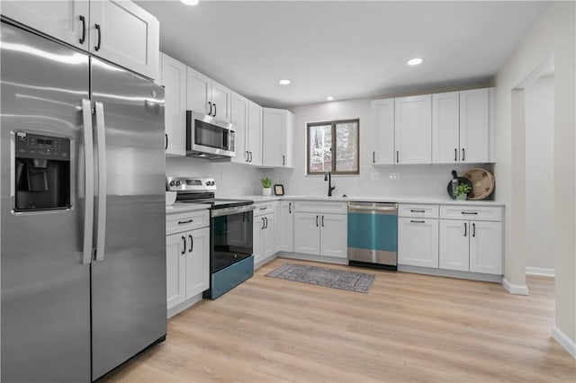 kitchen featuring stainless steel appliances, white cabinetry, tasteful backsplash, and sink