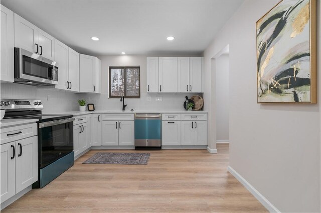 kitchen with white cabinets, stainless steel appliances, decorative backsplash, sink, and light hardwood / wood-style flooring