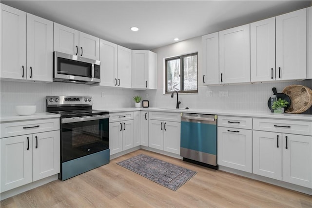 kitchen featuring white cabinets, light wood-type flooring, appliances with stainless steel finishes, and sink