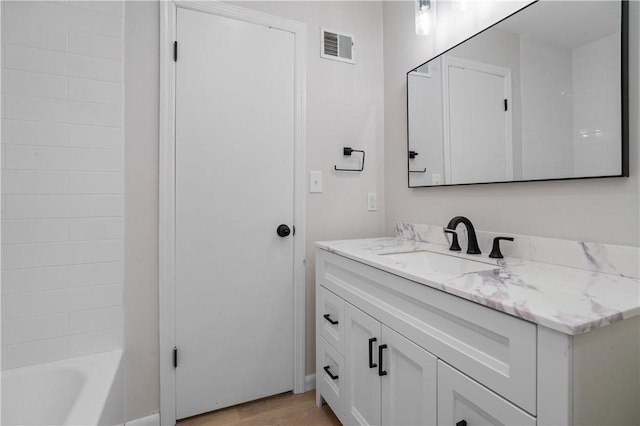 bathroom featuring washtub / shower combination, wood-type flooring, and vanity