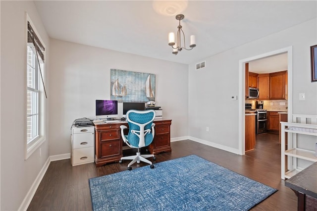 office space with a healthy amount of sunlight, dark hardwood / wood-style flooring, and a chandelier