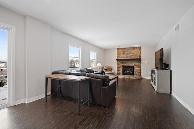 living room featuring dark hardwood / wood-style flooring and a stone fireplace