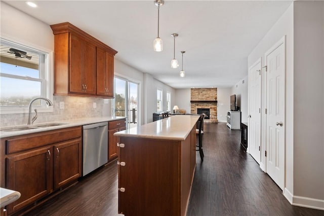 kitchen featuring dark hardwood / wood-style floors, a center island, dishwasher, hanging light fixtures, and sink