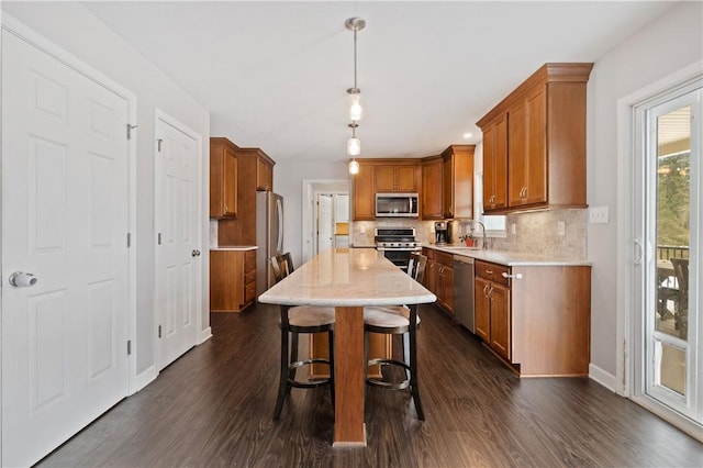 kitchen featuring pendant lighting, a kitchen island, a kitchen bar, sink, and stainless steel appliances