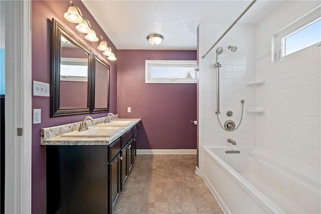 bathroom with a textured ceiling, vanity, and tiled shower / bath