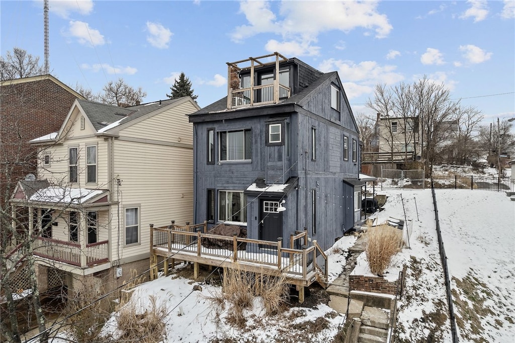 snow covered house featuring a deck