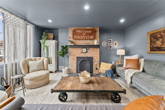 living room featuring a brick fireplace and light hardwood / wood-style floors