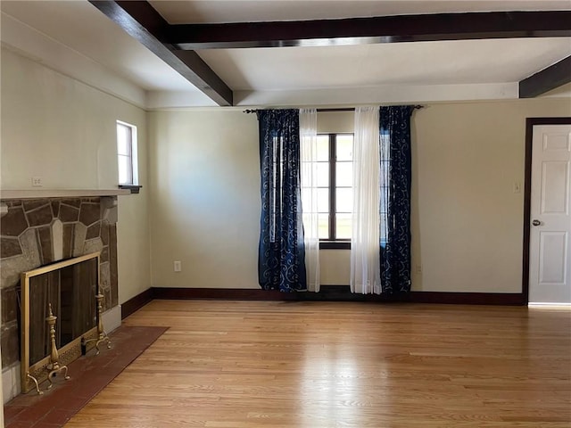 living room with a fireplace, beam ceiling, and light wood-type flooring