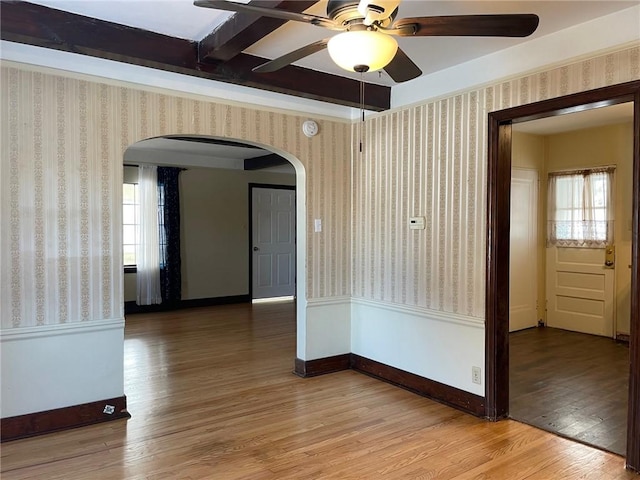 spare room with hardwood / wood-style flooring, beamed ceiling, ceiling fan, and a wealth of natural light