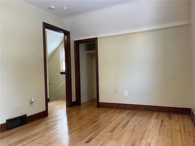 unfurnished bedroom featuring a closet, lofted ceiling, and light hardwood / wood-style flooring