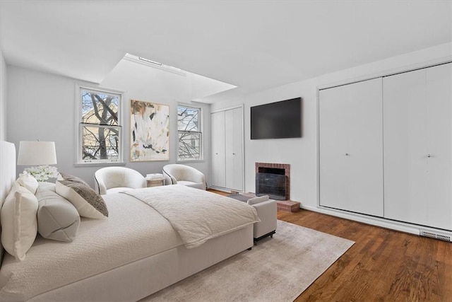 bedroom featuring multiple closets, a fireplace, and hardwood / wood-style floors