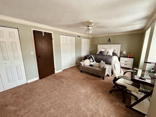 carpeted bedroom with multiple closets, ceiling fan, and ornamental molding