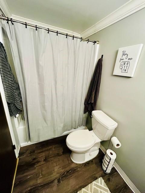 bathroom featuring wood-type flooring, ornamental molding, and toilet