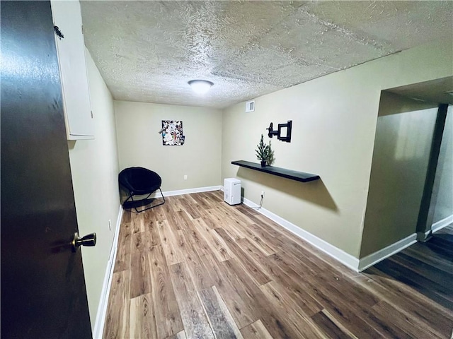 unfurnished room with hardwood / wood-style flooring and a textured ceiling