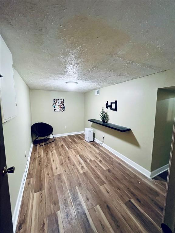 unfurnished room with wood-type flooring and a textured ceiling