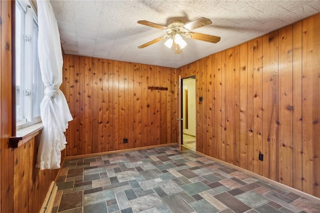 unfurnished room featuring ceiling fan and wooden walls