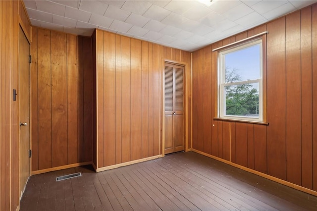 spare room featuring dark hardwood / wood-style floors and wooden walls