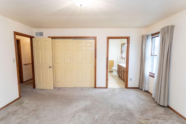 unfurnished bedroom featuring light colored carpet, a closet, and connected bathroom