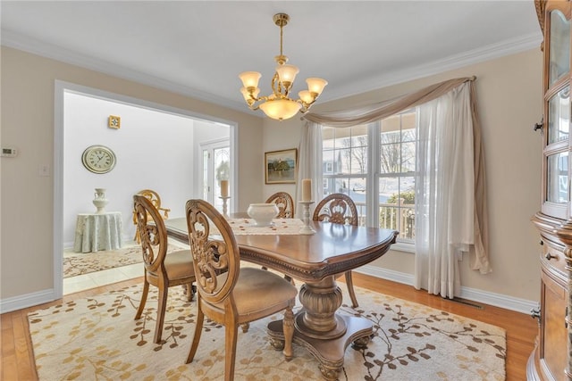 dining space with an inviting chandelier, crown molding, and light hardwood / wood-style flooring