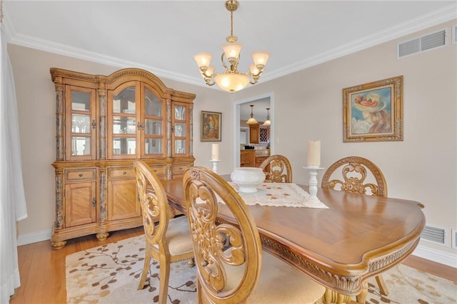 dining room featuring a notable chandelier, crown molding, and light hardwood / wood-style flooring