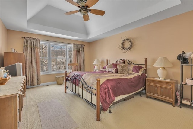 bedroom featuring a raised ceiling, ceiling fan, and light carpet