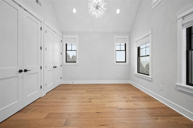 unfurnished bedroom featuring lofted ceiling, light wood-type flooring, and multiple windows