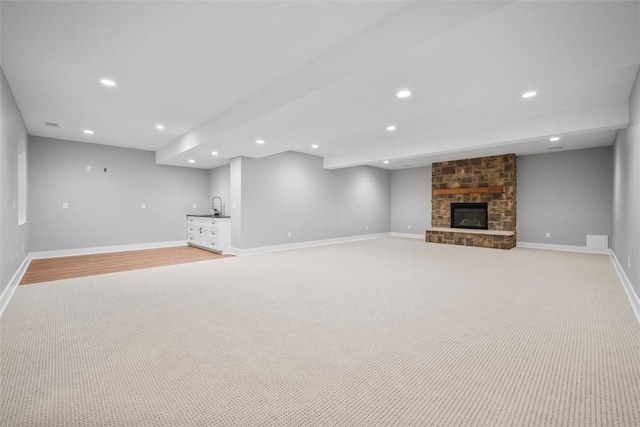 unfurnished living room featuring indoor wet bar, light carpet, and a fireplace