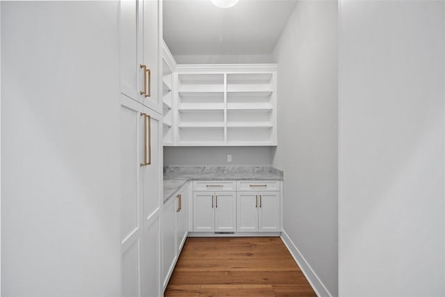 interior space with light stone countertops, white cabinetry, and light wood-type flooring