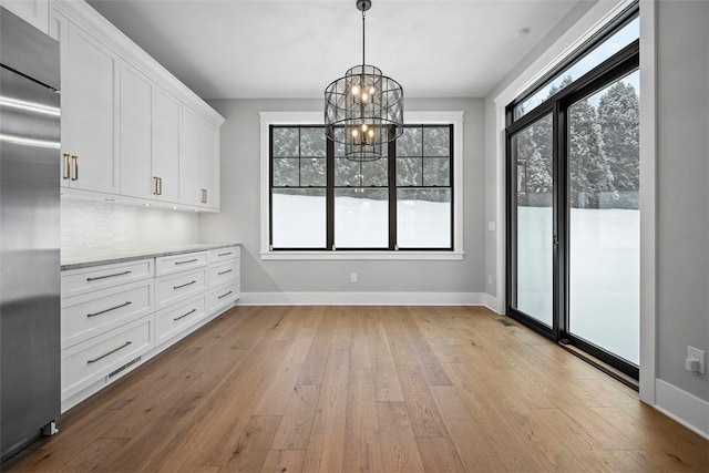 unfurnished dining area featuring plenty of natural light, light hardwood / wood-style flooring, and a chandelier