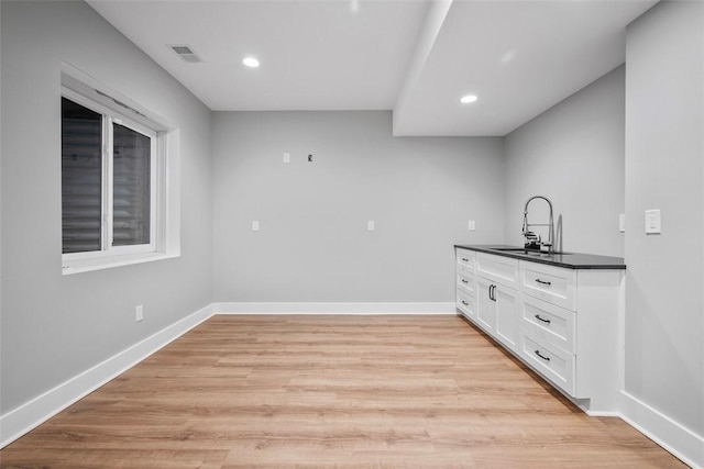 bar with white cabinetry, light hardwood / wood-style floors, and sink